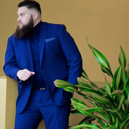 homme barbu portant un costume bleu électrique sur un fond jaune