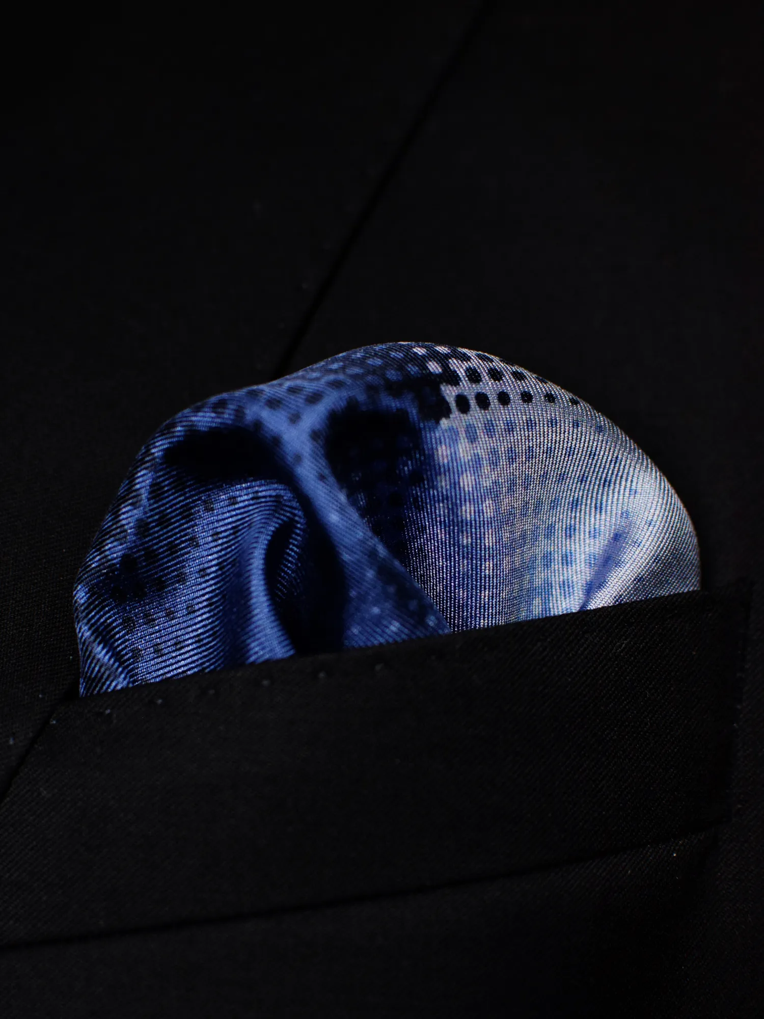 Pochette Lanvin bleue portée dans une veste noire, pli bouffant révélant les pois.
