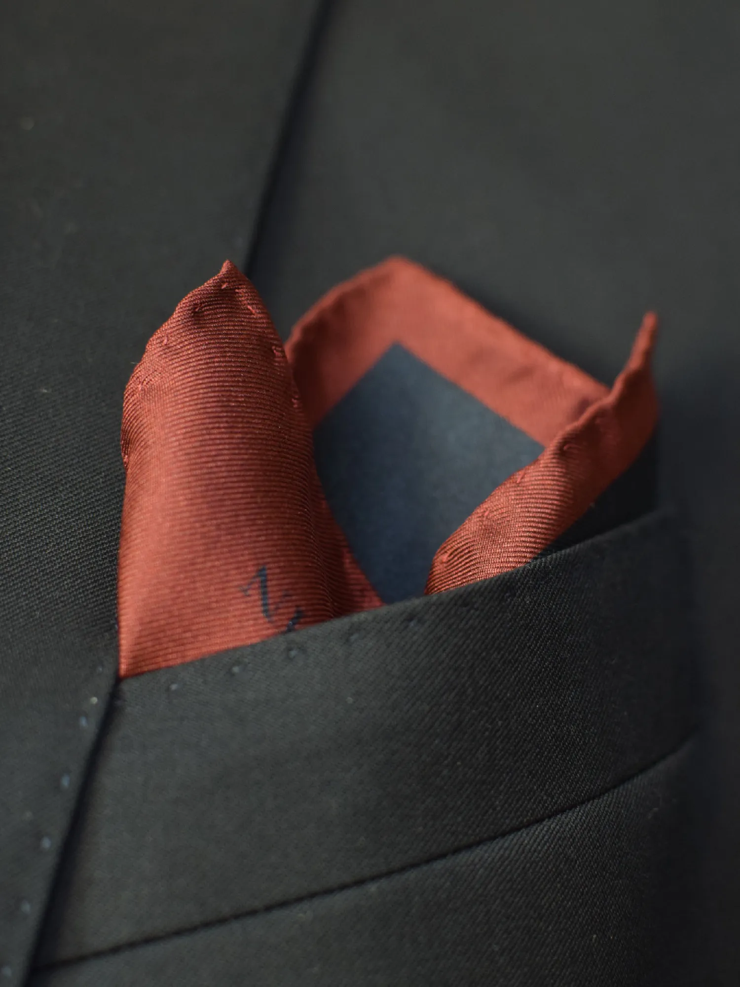 Pochette Lanvin portée en pli droit, avec bords visibles et teintes bordeaux et noir contrastantes.