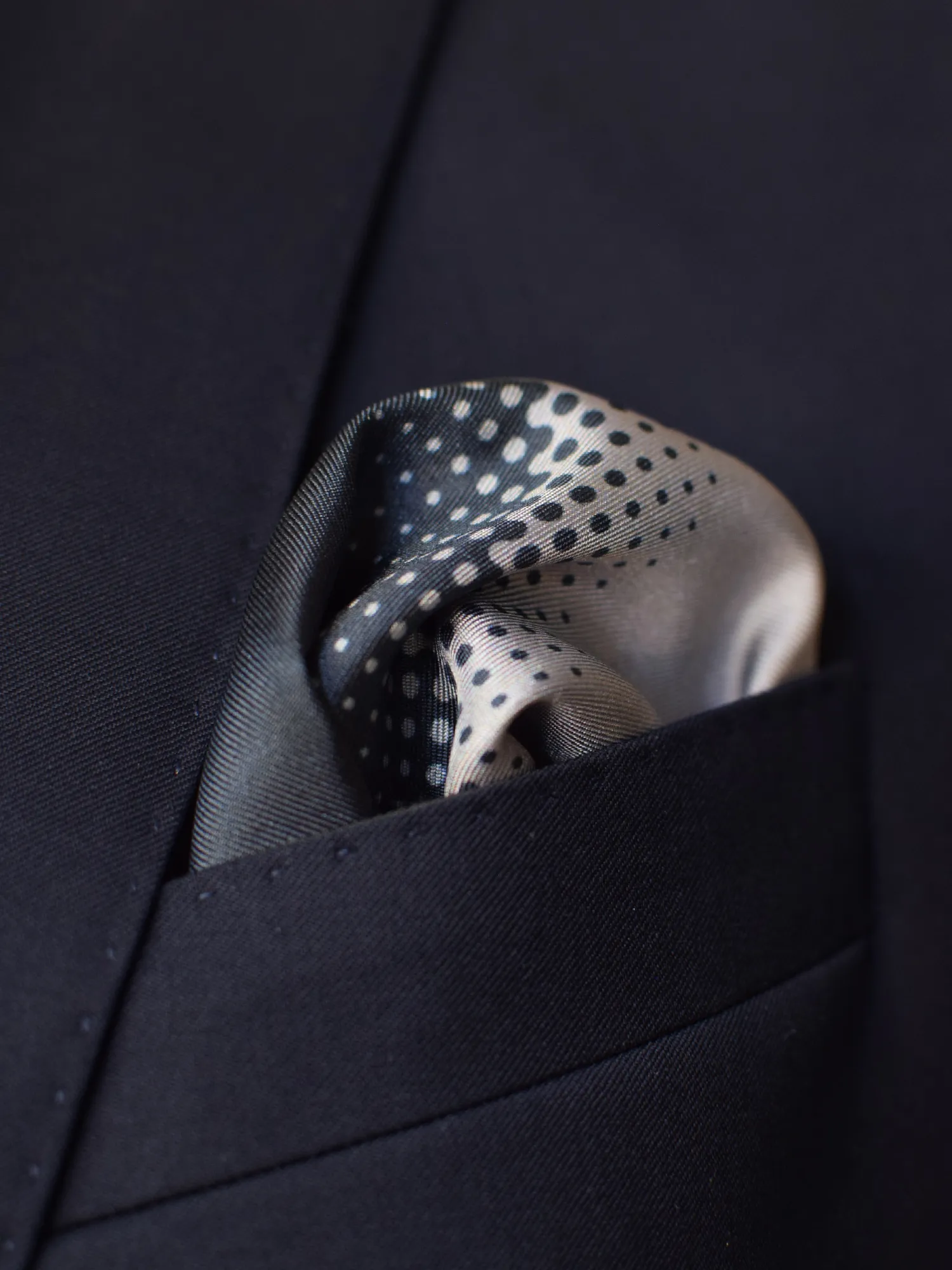 Pochette Lanvin à dégradé gris portée dans une veste foncée, pliage bouffant.