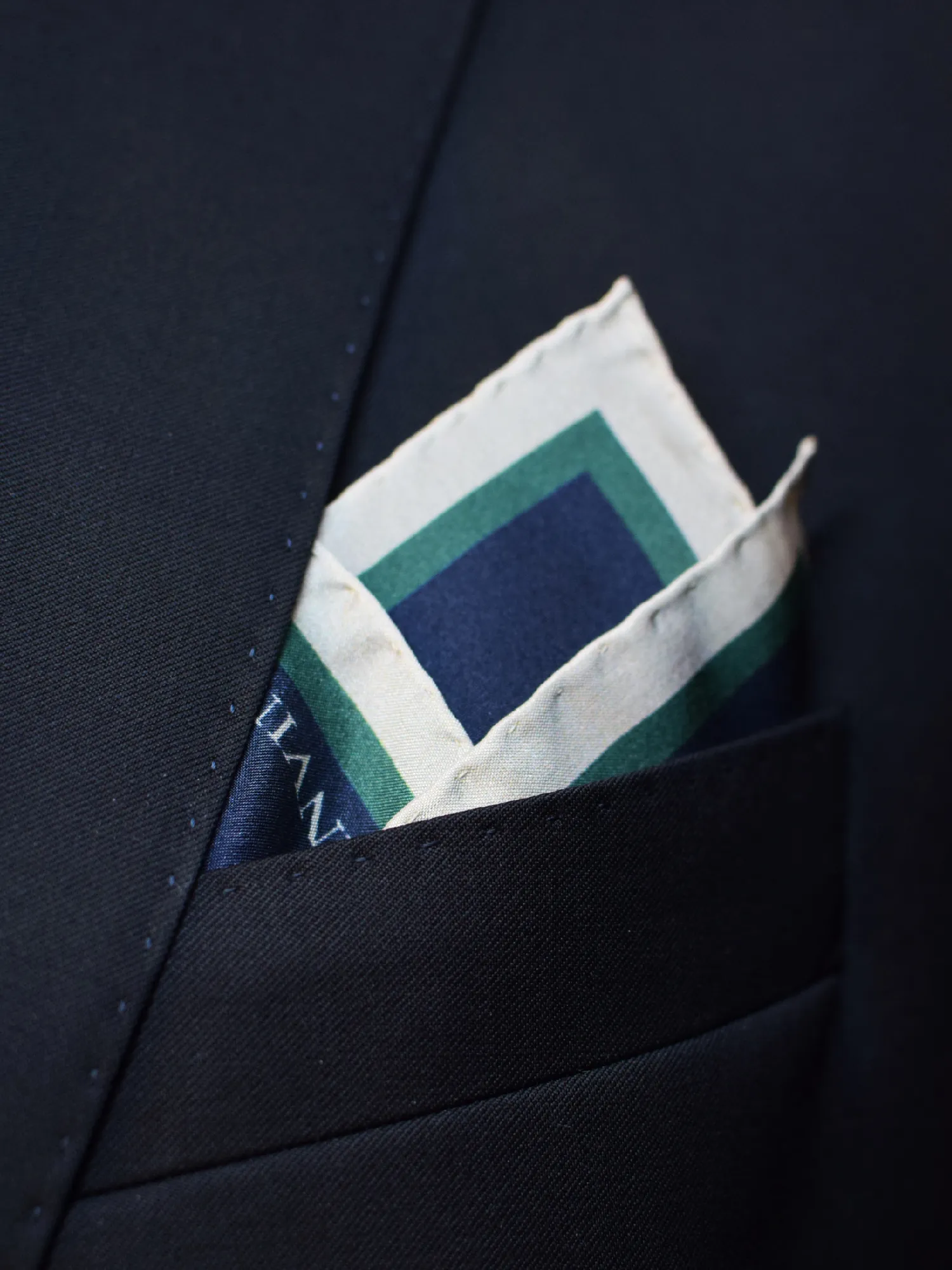 Pochette Lanvin bleu marine portée, pliure angulaire laissant apparaître les liserés.
