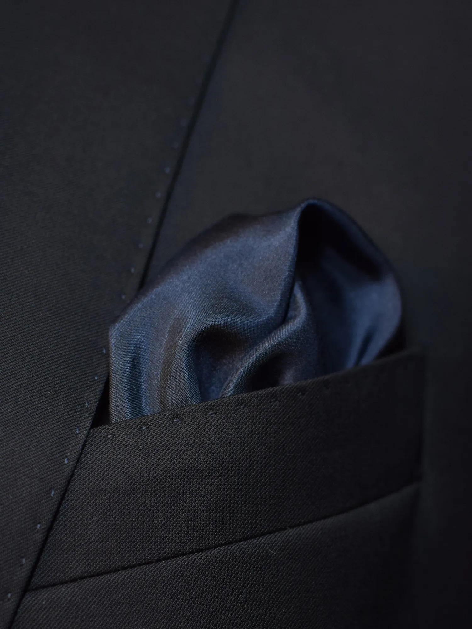 Pochette Lanvin bleu marine portée, pli bouffant révélant la profondeur de la soie.