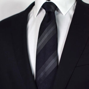 Cravate club noire et grise en soie portée sur chemise blanche
