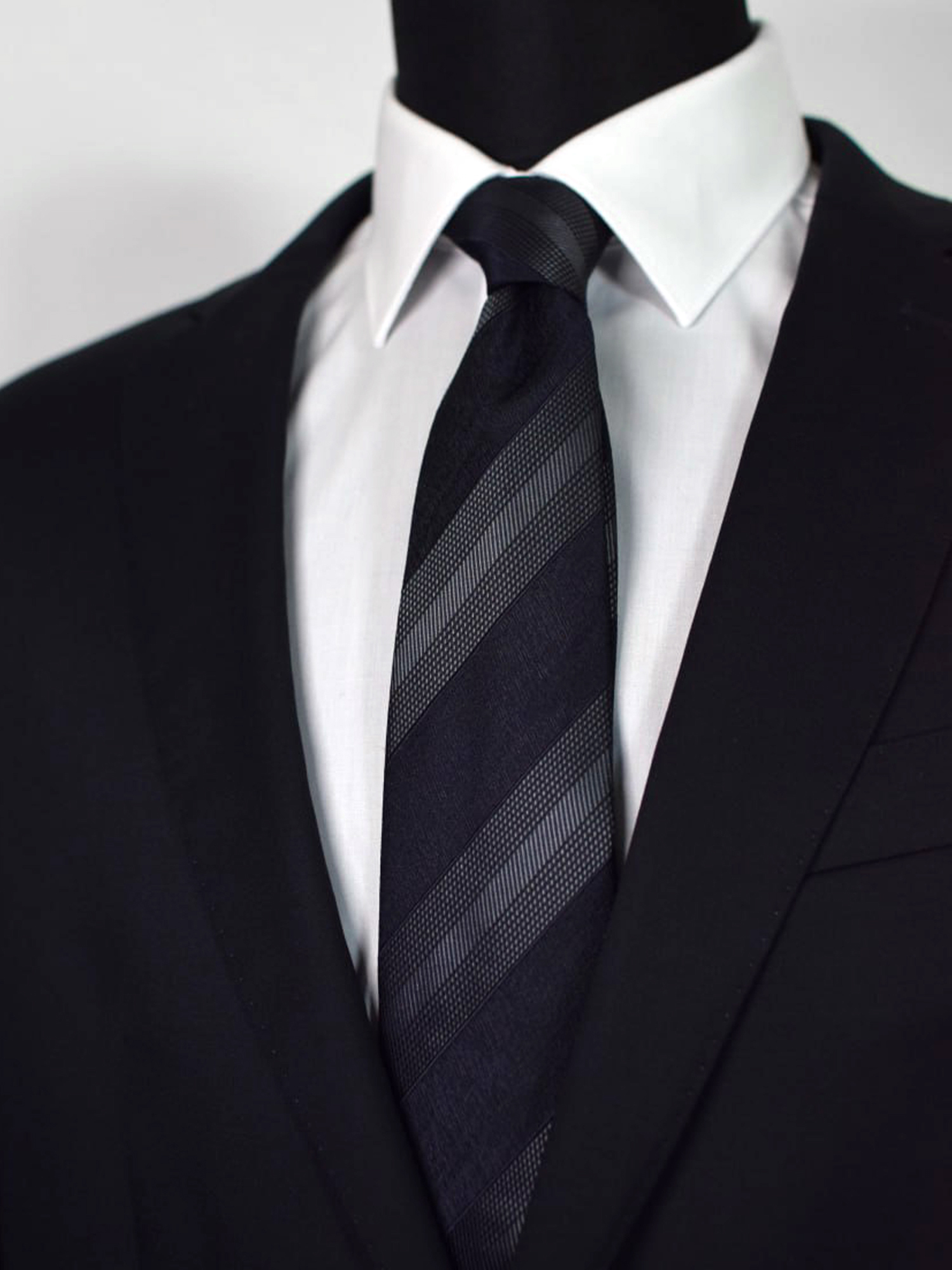 Cravate club noire et grise en soie portée sur chemise blanche